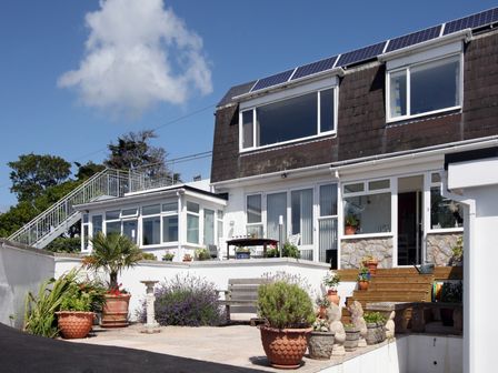 Exterior view of a two story house with a patio garden and potted plants at Rosa in Torquay