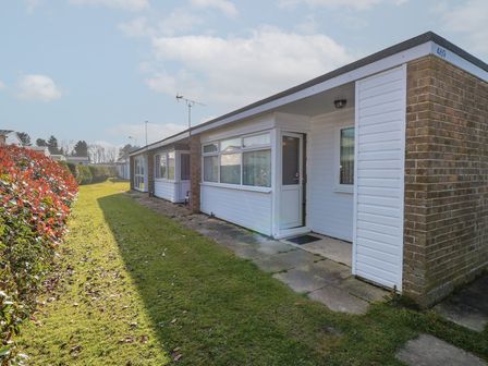 A row of single-story homes with grass and hedges outside at Chalet 469 in Newport Norfolk