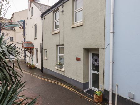 A narrow street with houses on both sides and plants in pots near the entrances at Pie Cottage in Teignmouth