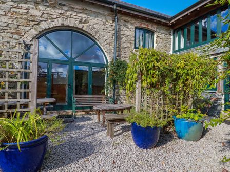 A garden with a wooden bench and table at Stribleys Barn, Cusgarne, Truro