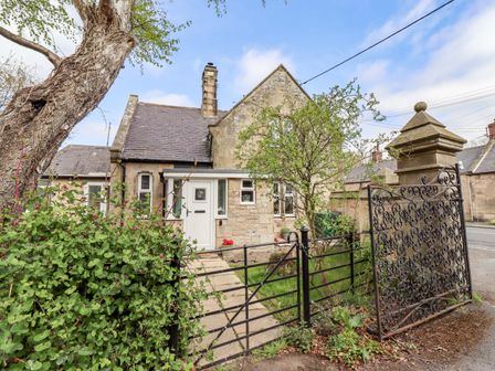 A house with a gate and tree at The Lodge in Powburn