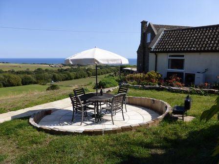 An outdoor seating area with a table and chairs at Meadow Cottage in Staintondale near Cloughton