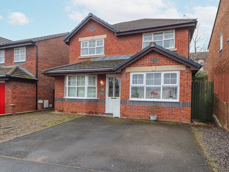 A red brick detached house with a driveway and white-framed windows at Marwood in Penrith