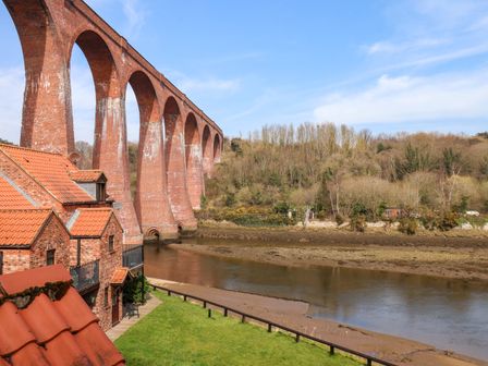 A river with a large brick viaduct bridge and houses with tiled roofs beside the river at No 15 Riverside Walk Mallard in Whitby
