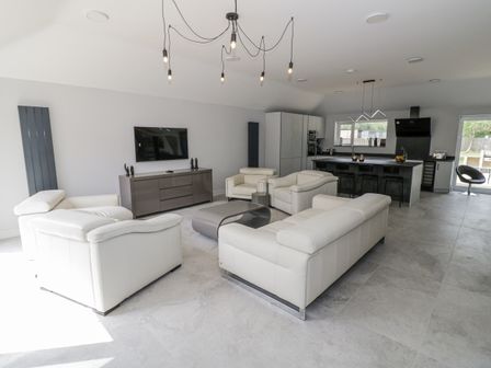 A living room with a television and kitchen island at Chillon South Littleton near Honeybourne