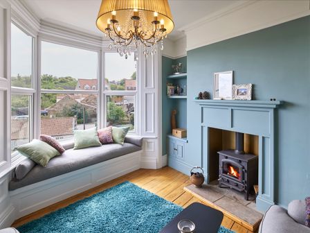 A living room with a fireplace and window seat at Isla House in Whitby