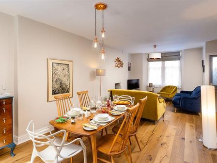 A dining table with place settings and wooden chairs in a living room with yellow and blue sofas at Bellflower Cottage in Windermere
