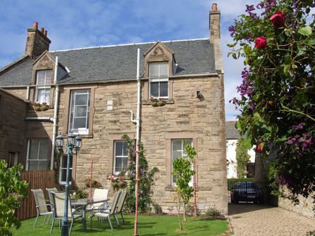 A stone house with windows and flower boxes a garden with outdoor furniture and a lamp post at Bank View in Chirnside