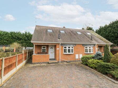 A brick semi detached house with skylights and a paved driveway surrounded by fencing and shrubbery at Rooster in Stourport-On-Severn