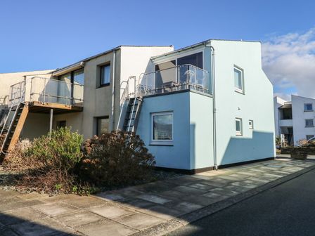 A two story building with external staircases and balconies with glass railings at The Moorings Apartment in Porthmadog