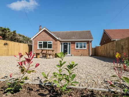 A single story brick house with a gravel yard and plants in front at The Hideaway in Bempton near Flamborough