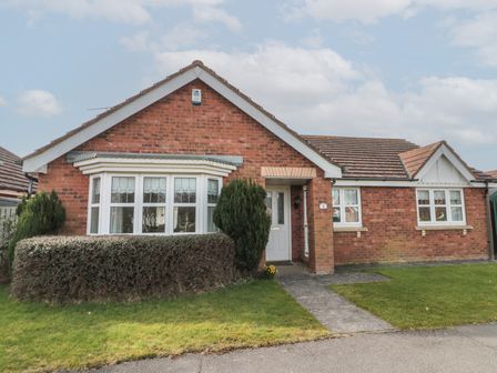 A single-story brick house with a bay window a hedge and a pathway leading to a white front door at Bray Nook 7 Craikewells in Flamborough