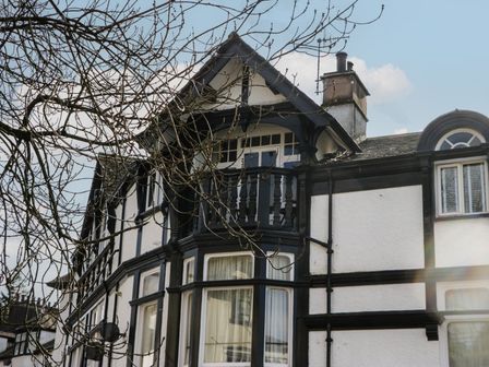 An exterior view of a two-story house with black and white timber framing and a small balcony on the upper floor at Two West End in Bowness-On-Windermere