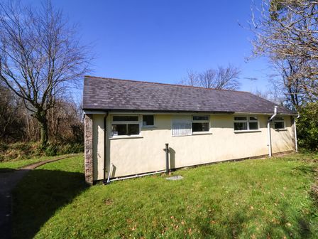 An exterior side view of a single story building with grass and trees at 24 The Glade in Kilkhampton