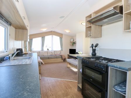 A kitchen with a countertop and stove next to a living area with a sofa and television at 31B Foxburrow Hang in Fritton near Belton Norfolk