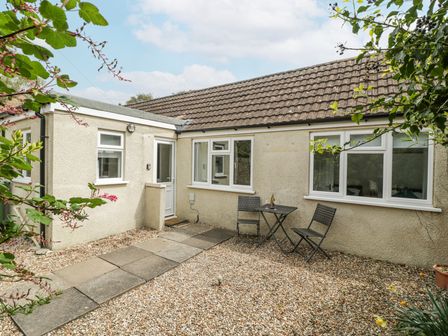 A small patio area with two chairs and a table outside a single story house at Spring Cottage in Birdlip near Brockworth