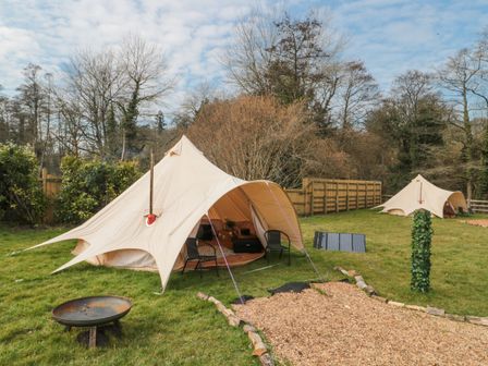 Two bell tents set up on grass with chairs a fire pit and solar panels at Bell tent 3 Camerton near Timsbury