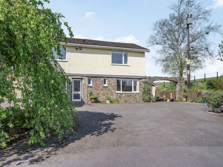 A two story house with stone and cream exterior walls a large driveway and various plants at Pant Y Cwtsh in Kidwelly