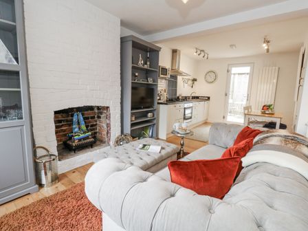 A living room with a fireplace and kitchen visible at Fisherman’s Cottage