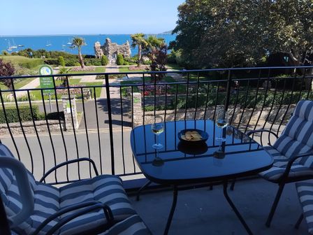A balcony with a table and chairs overlooking a garden and sea at The View in Weymouth