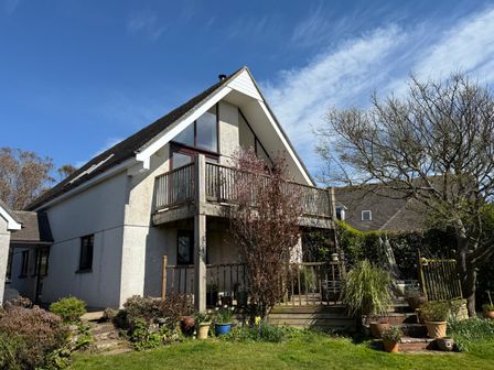 A house with a balcony and garden with plants and trees at 6 The Links in Praa Sands