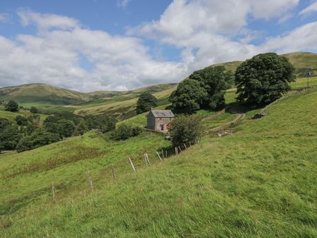 A cottage surrounded by trees and hills at Howgill Head in Kendal