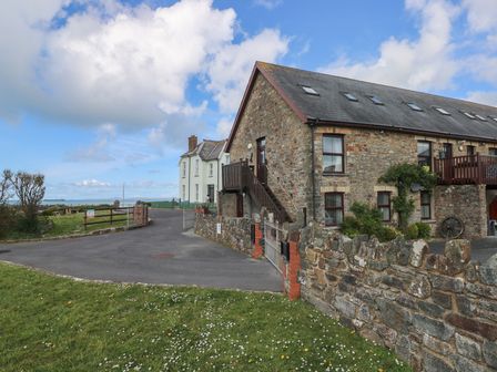 A brick building with stairs and a stone wall at Puffin Nook in Broad Haven
