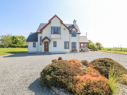 A two-story house with a gravel driveway and shrubs in front at Laceys Harbour in Duncannon County Wexford