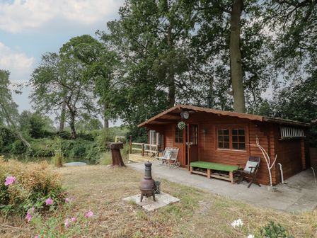 An outdoor area with a cabin and seating at Carps Well Lodge in Hatton near Shrewley