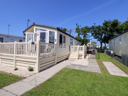 A mobile home with a deck and pathway at 152 Central Park in Prestatyn