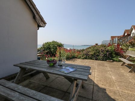 An outdoor area with a table, bottle and glasses at Sea Spray in Bowleaze