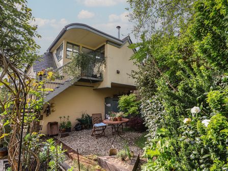 A garden area with plants gravel and outdoor furniture next to a house with stairs at Bentley Rise Lyme Regis