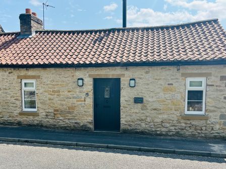 A cottage exterior with a door and windows at St Gregory’s Cottage in Oswaldkirk near Helmsley