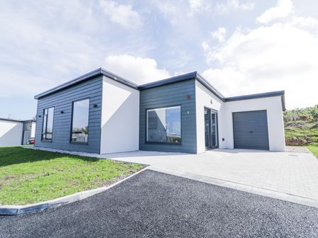 A modern single-story house with dark paneling and white walls with a driveway and garage at Number 5 Villa - The View in Derrybeg County Donegal