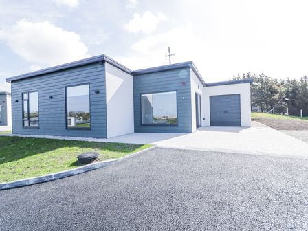 A modern single-story house with large windows a garage and paved driveway at Number 6 Villa - The View in Derrybeg County Donegal