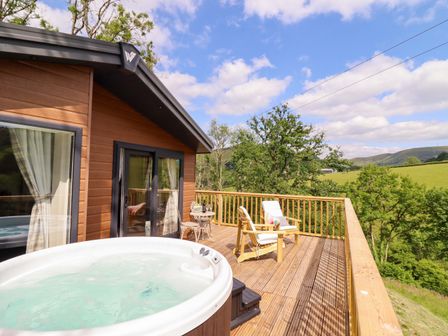 An outdoor space with a hot tub and chairs at The Owlet in Dolwen near Llanidloes