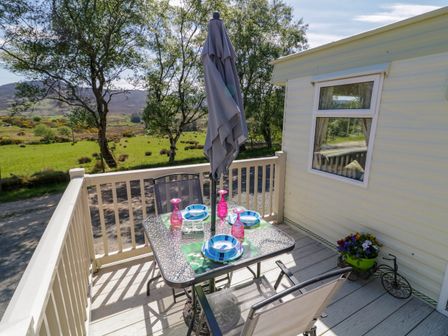 A patio with a table set for four and an umbrella next to a caravan at The Caravan@Meenacross in Cranford near Carrigart County Donegal