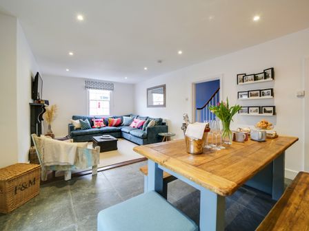 A living room with a sofa and dining area at Church Hill House Port Isaac
