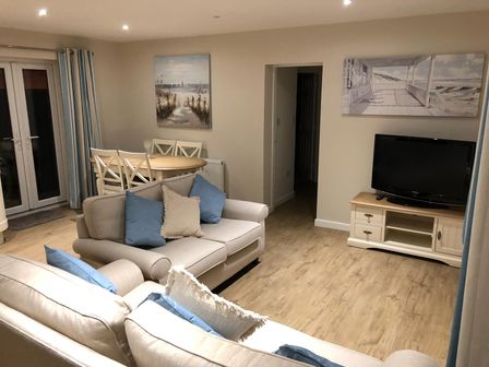 A living room with a sofa and dining area at Pen Y Ffrith Lodge in Prestatyn
