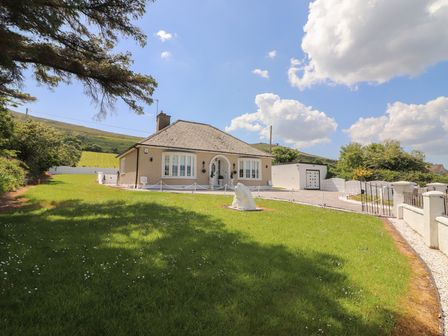A detached bungalow house with a front garden and driveway under a blue sky at Killelton Cottage in Camp County Kerry