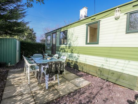 An outdoor patio area with a table and chairs at Meadow Island Caravan in Penygroes