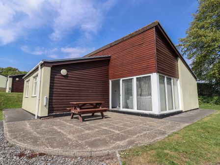 A house with a patio and table at Babbacombe Breeze in Chudleigh