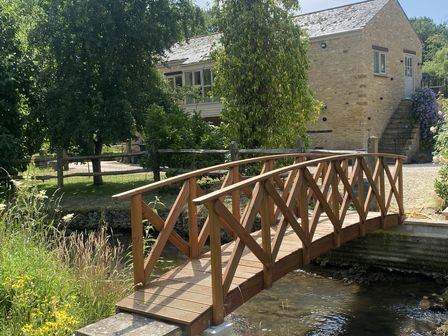 A wooden bridge over a stream near a building at The Annexe, Cleveley Mill in Enstone