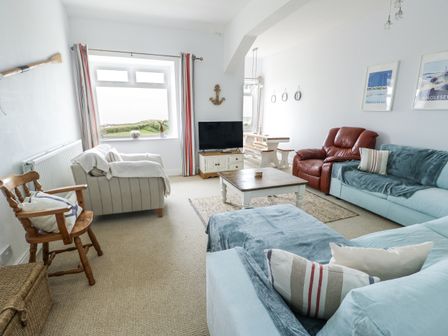A living room with a sofa and a television at Lady of the Lake Suite Trearddur Bay