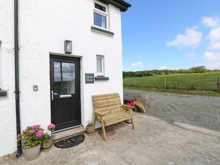 An entrance with a bench and flowers at Coach House Cottage