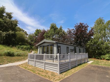 A house with a deck and trees at The Pines 2 Bedrooms in Delamere