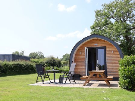 A wooden cabin with a table and chairs at Honeypot Hideaways - Acacia
