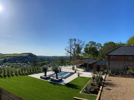 A backyard with a small pool two trees patio seating and a house with a garden at Forest View in Pontyclun