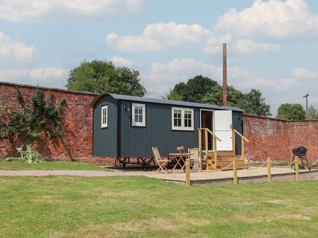A shepherd's hut with outdoor seating area at Shepherd's Hut in Wrexham