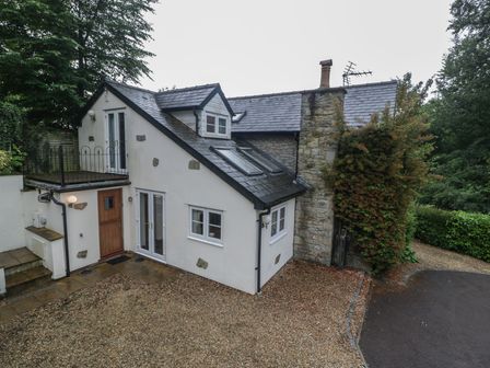 A house with a stone wall and a balcony at Wren Cottage in Ross-on-Wye
